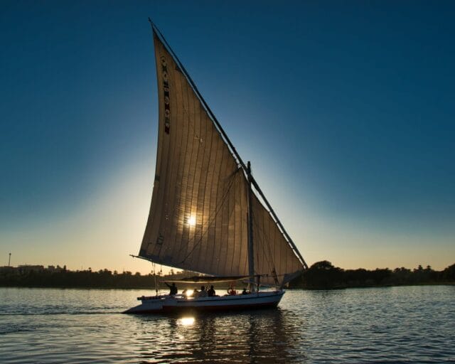 a sailboat sailing on the water at sunset